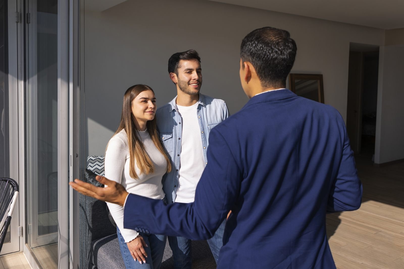 Casal conversando com consultor imobiliário dentro de um apartamento